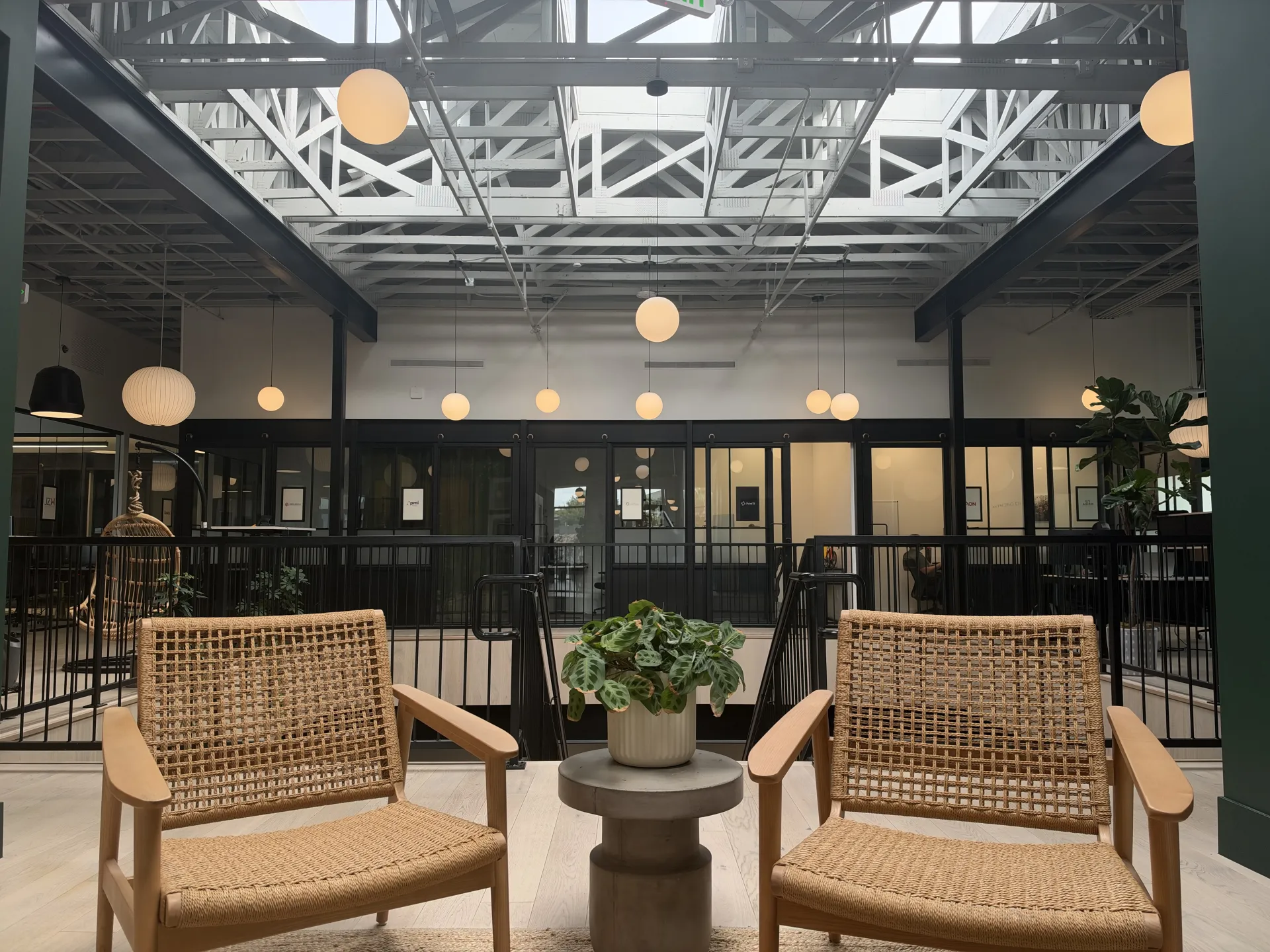 A bright lounge inside Kiln St. George with two chairs, plants, and exposed timber rafters