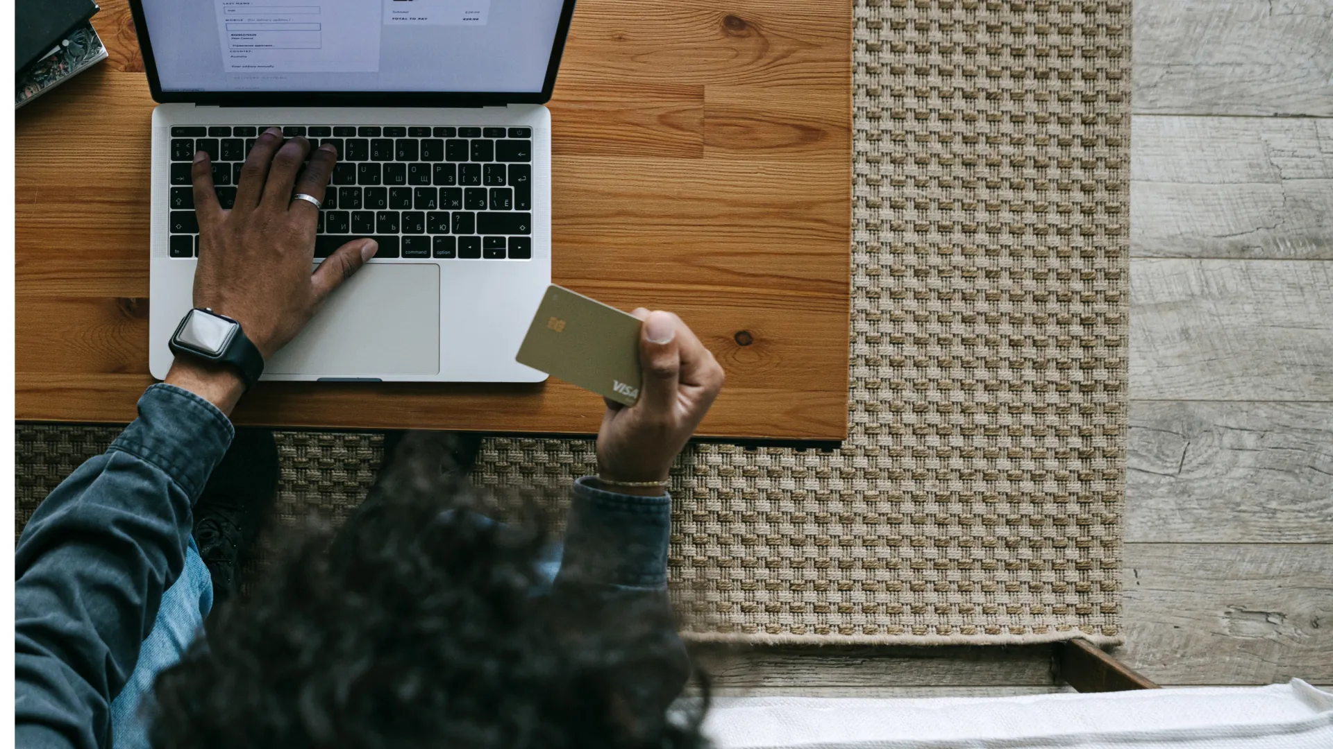 A customer holding a card while shopping on a laptop