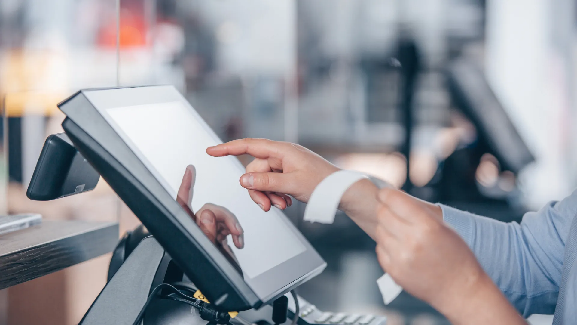 A hand selecting an option on a point-of-sale screen