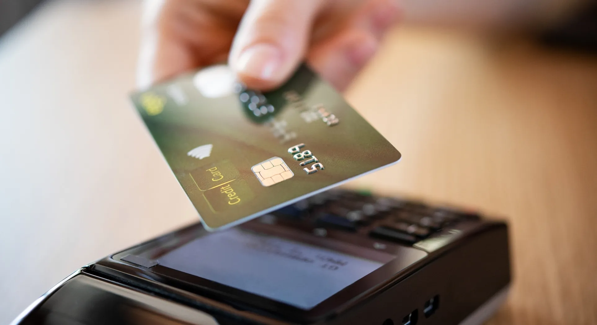 A customer tapping a card on a payment terminal at a counter