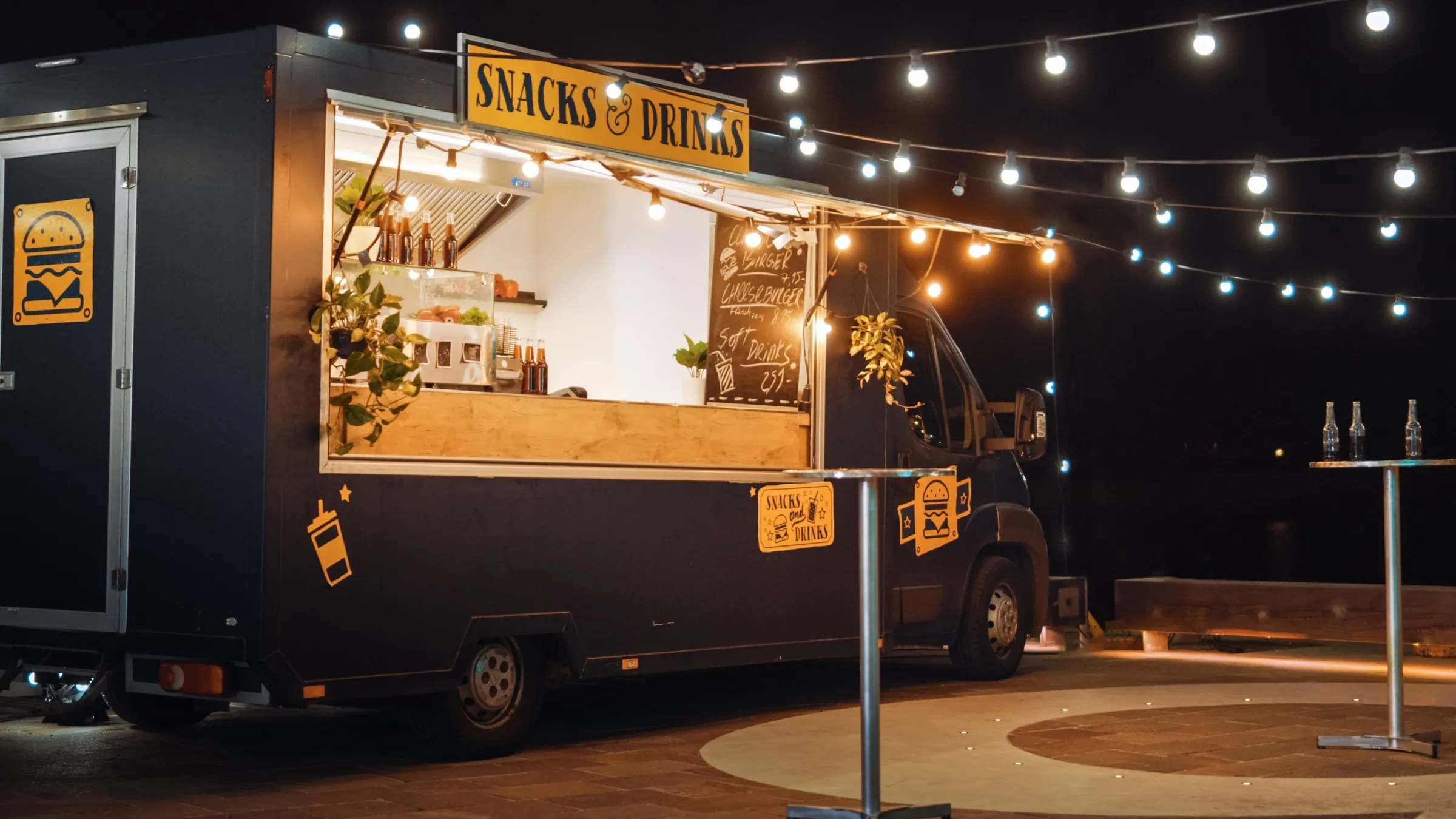 A food truck lit with string lights at night