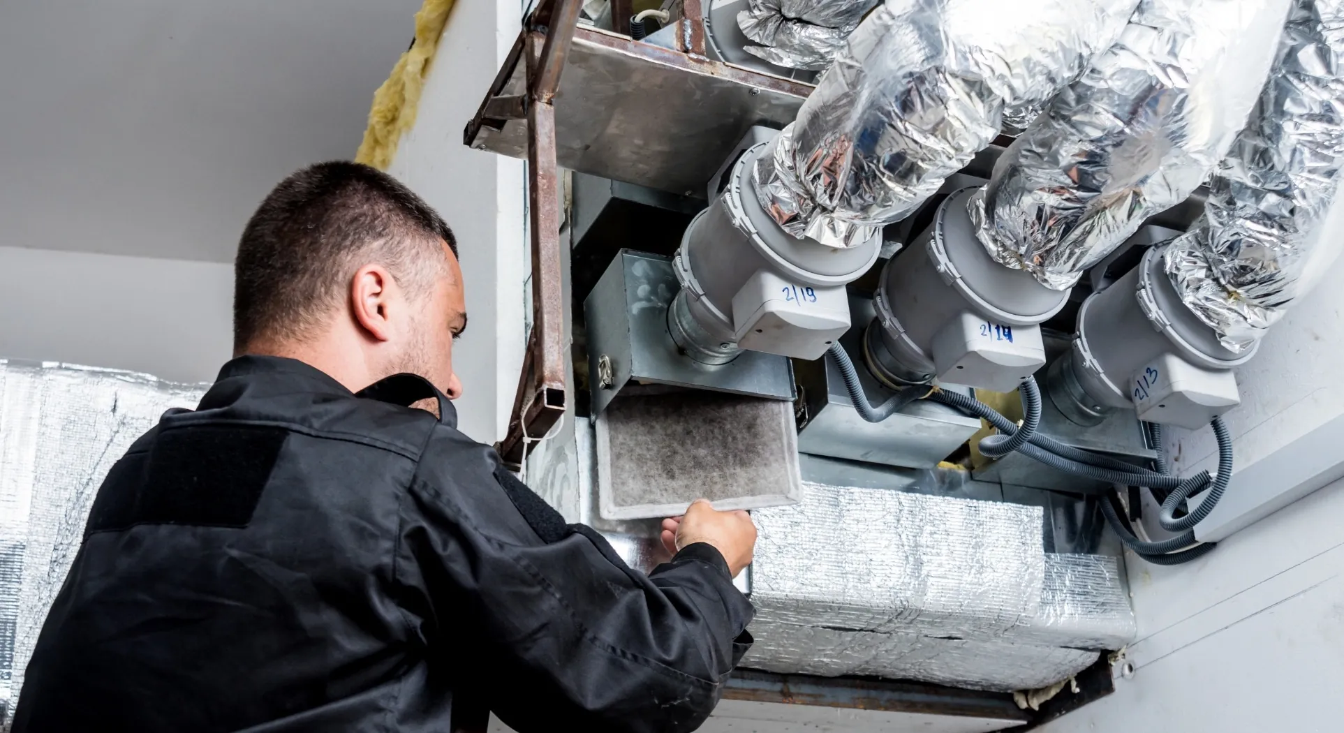 An HVAC technician working on ductwork