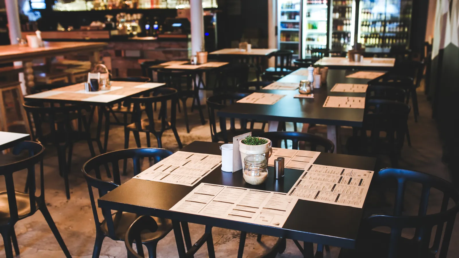 An empty cafe interior with black tables and menus set out for the day
